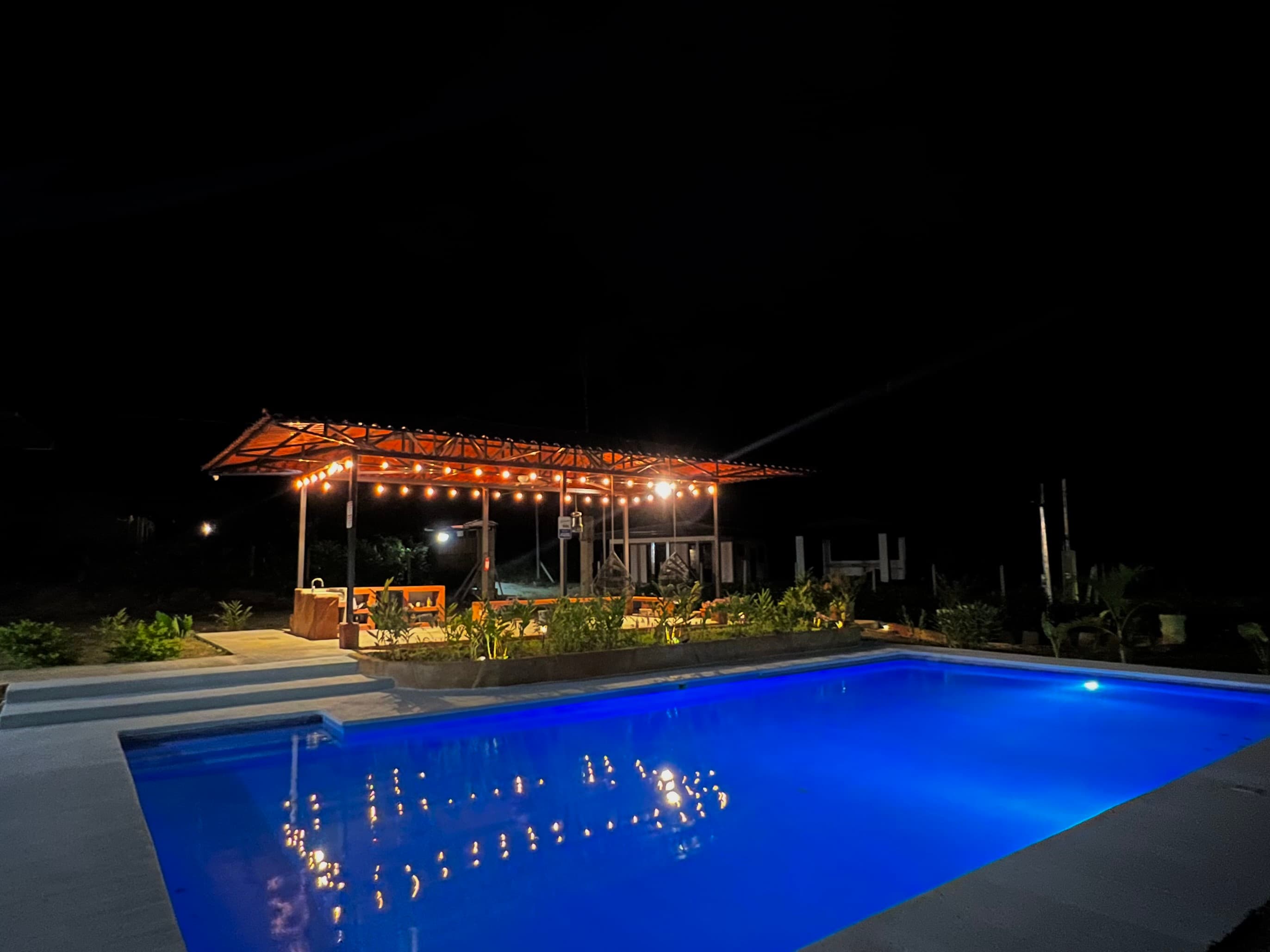 The pool lit at night, the rancho glowing behind it